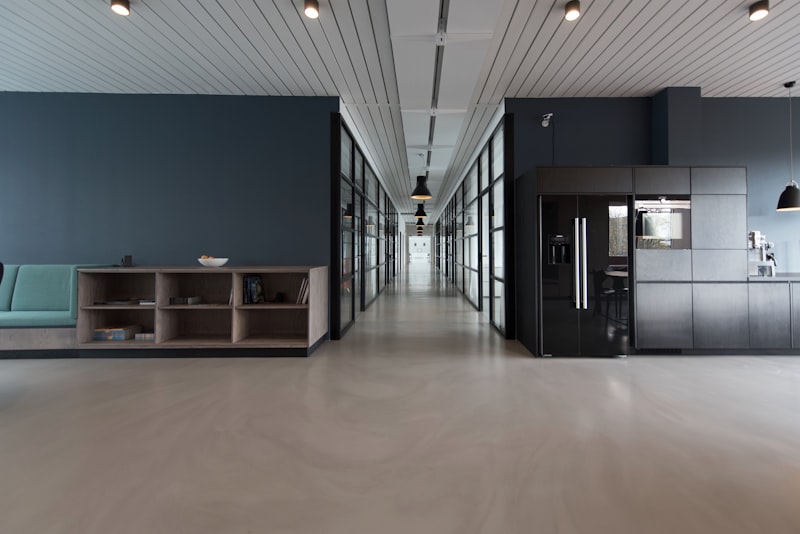 Open-plan office with glass-walled rooms, a central hallway, navy accent wall, and kitchen area