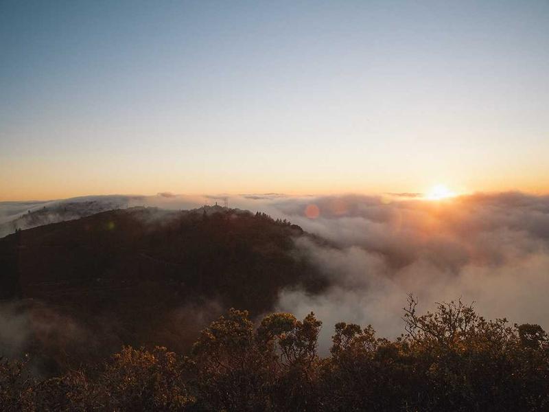 Golden sunrise over a fog-filled valley between dark mountain ridges